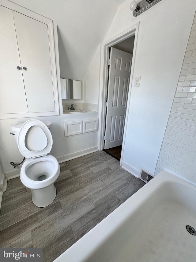 bathroom featuring a bath, toilet, and sink