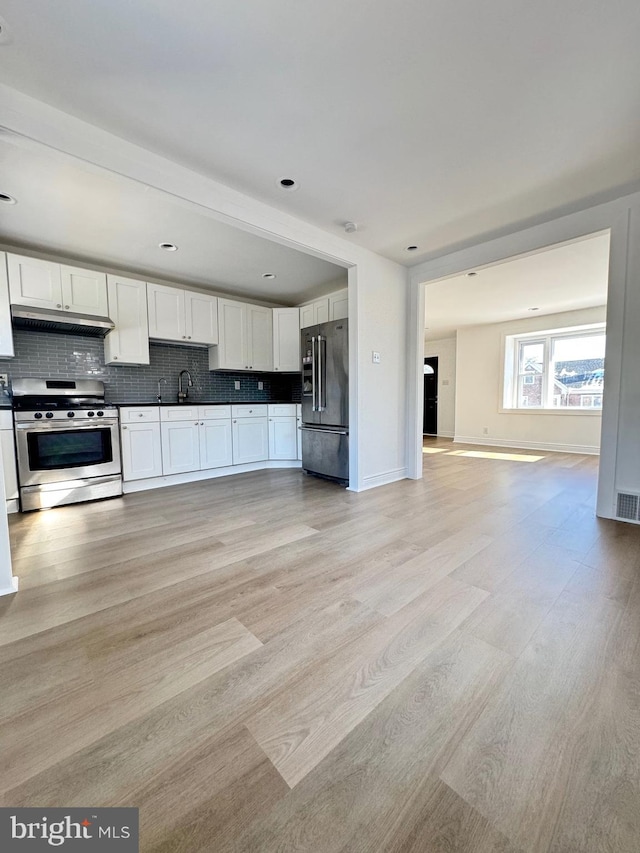 kitchen with white cabinetry, sink, light hardwood / wood-style flooring, backsplash, and appliances with stainless steel finishes