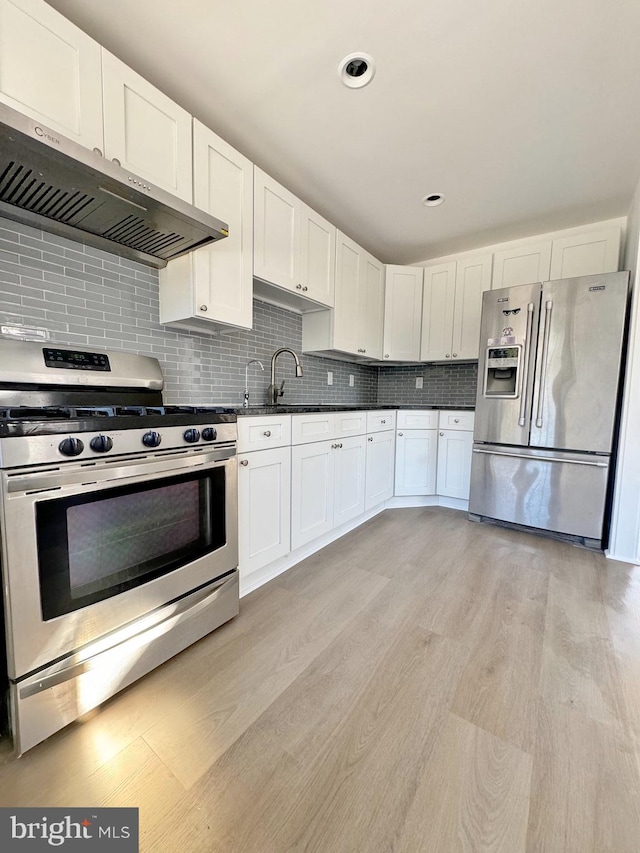 kitchen with light hardwood / wood-style flooring, white cabinets, stainless steel appliances, and extractor fan