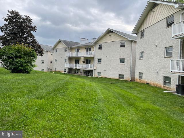 rear view of property featuring cooling unit and a yard