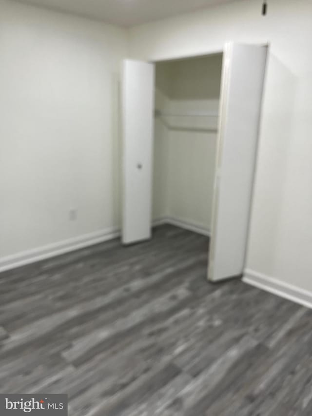 unfurnished bedroom featuring dark hardwood / wood-style flooring and a closet