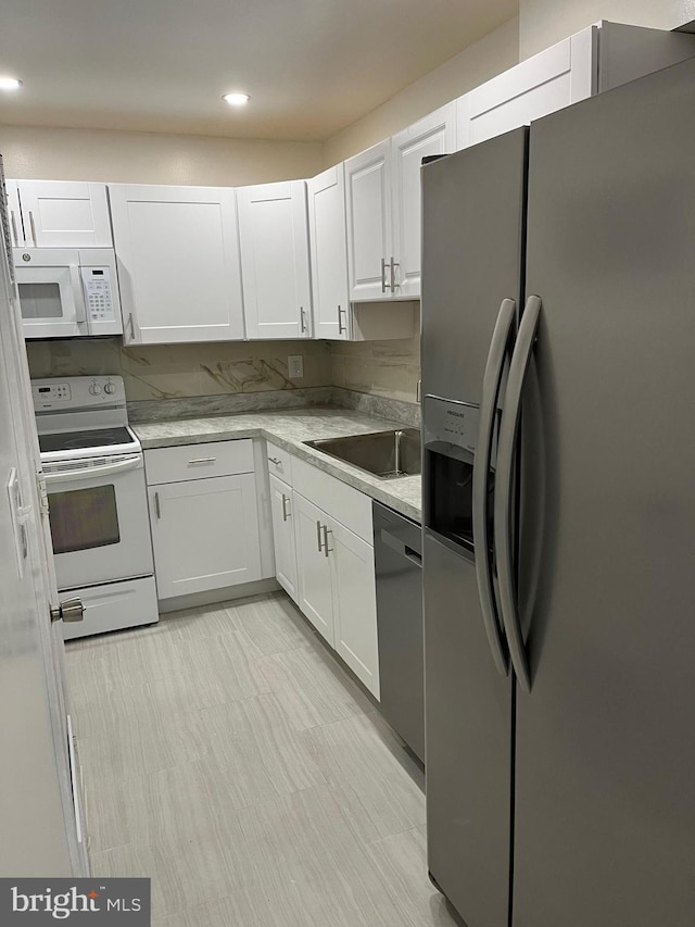 kitchen with light stone counters, sink, white cabinets, and stainless steel appliances