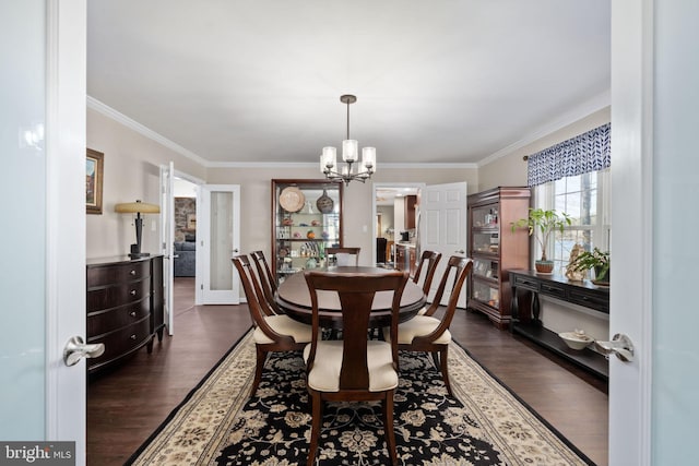 dining area with ornamental molding, an inviting chandelier, and dark wood-type flooring