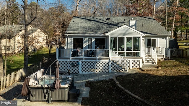 rear view of property with a sunroom and a hot tub