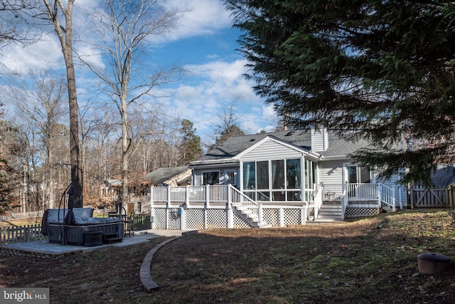 rear view of property with a wooden deck, a sunroom, and a hot tub