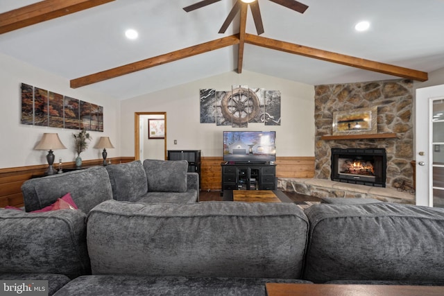 living room featuring a stone fireplace, ceiling fan, lofted ceiling with beams, and wood walls