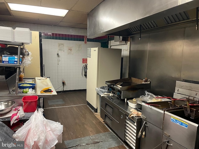 kitchen with ventilation hood, a paneled ceiling, white fridge, and dark hardwood / wood-style floors