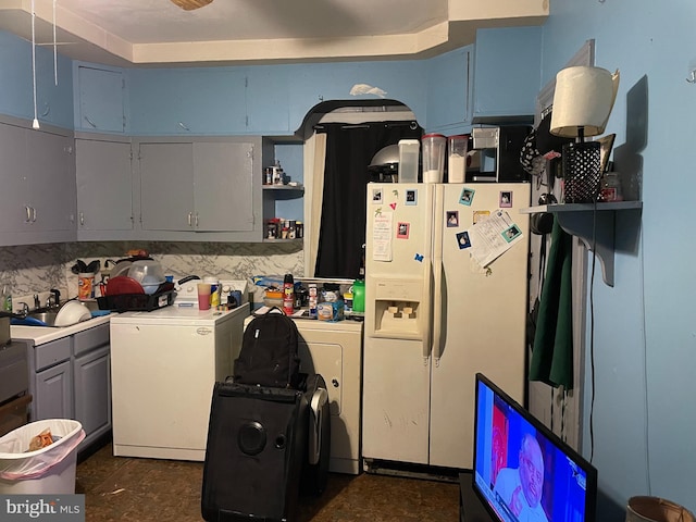 kitchen featuring washing machine and clothes dryer, sink, refrigerator, and white refrigerator with ice dispenser