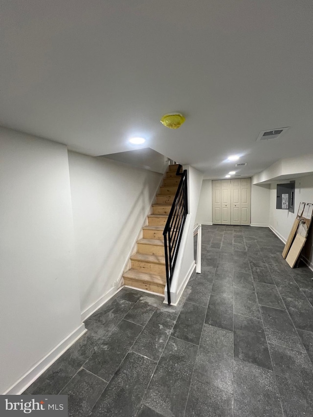 finished below grade area featuring baseboards, visible vents, and stairway