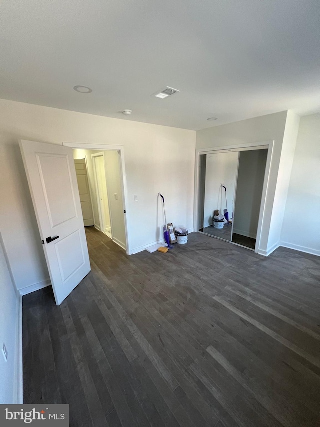 spare room with dark wood-type flooring, visible vents, and baseboards