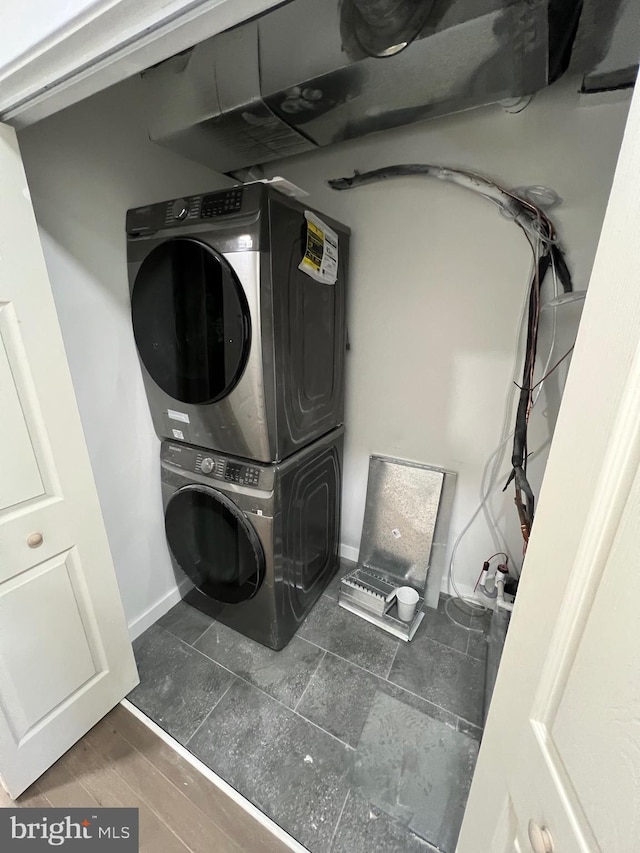 laundry area with laundry area, baseboards, and stacked washing maching and dryer