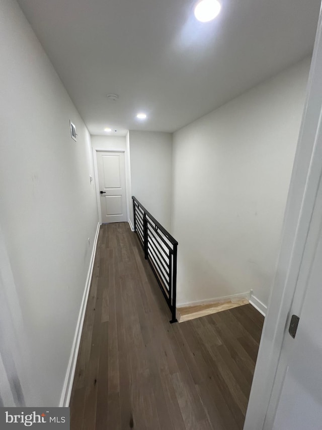 hall featuring visible vents, baseboards, dark wood-style flooring, and an upstairs landing