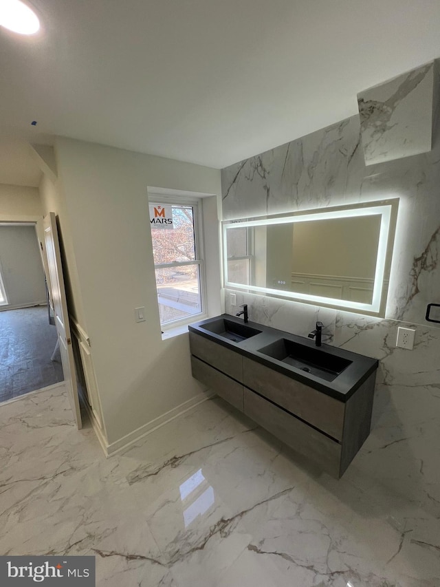 bathroom featuring marble finish floor, double vanity, and a sink