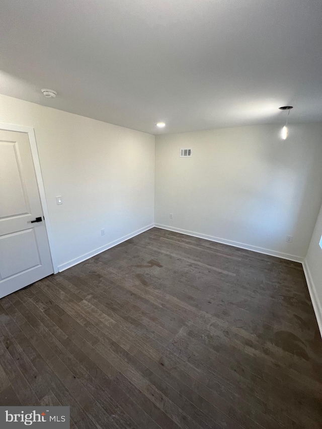 spare room featuring recessed lighting, dark wood finished floors, visible vents, and baseboards