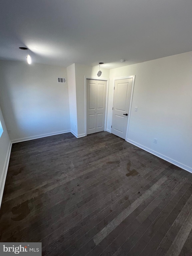 unfurnished room featuring baseboards, visible vents, and dark wood-style flooring