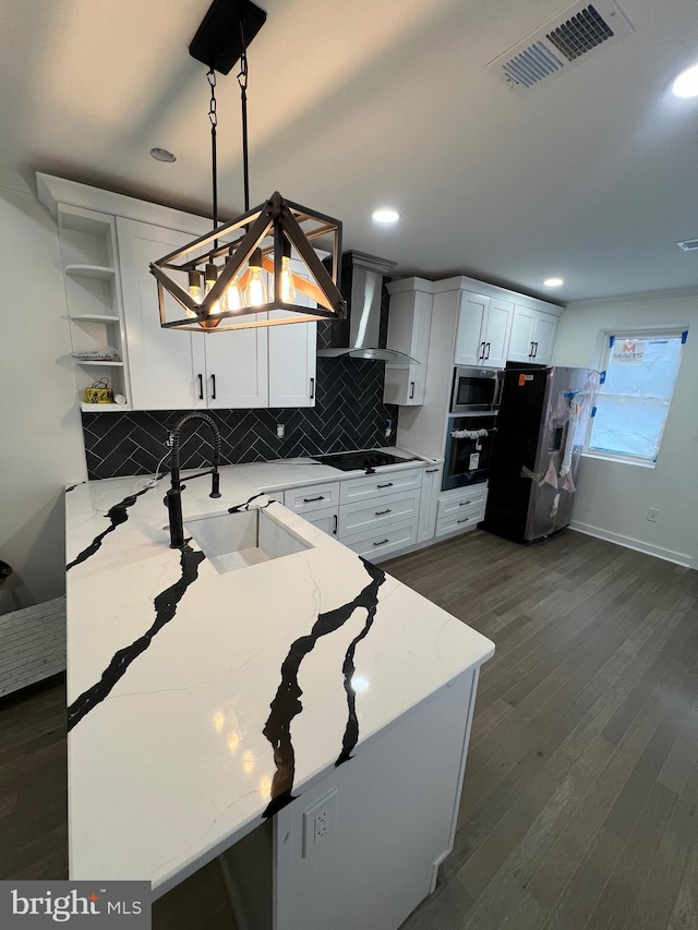 kitchen with light stone counters, visible vents, decorative backsplash, a sink, and black appliances