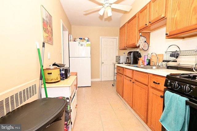 kitchen with gas stove, ceiling fan, sink, white fridge, and light tile patterned floors