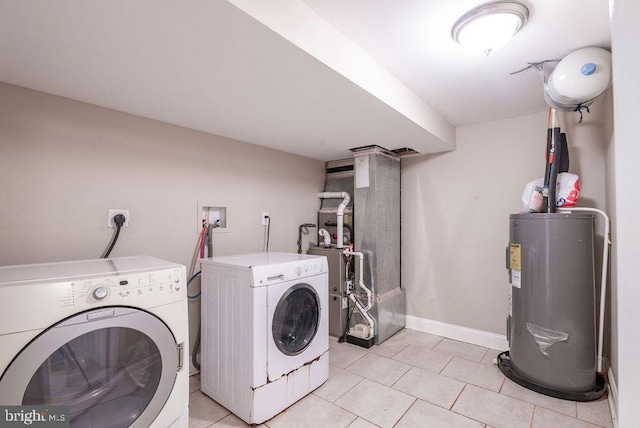 clothes washing area featuring electric water heater, washer and clothes dryer, and light tile patterned floors