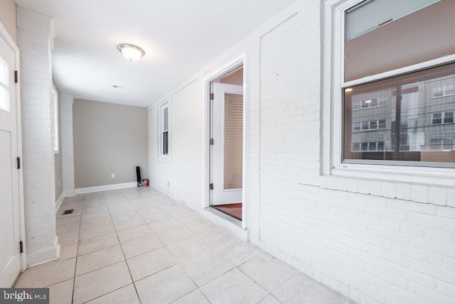 interior space with light tile patterned floors and brick wall