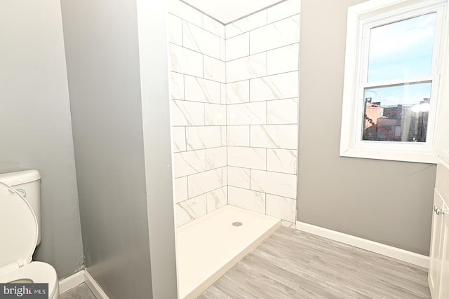 bathroom featuring a tile shower, hardwood / wood-style flooring, and toilet