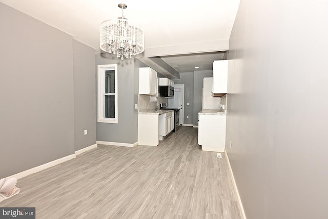 kitchen featuring white cabinetry, electric range, an inviting chandelier, pendant lighting, and light wood-type flooring