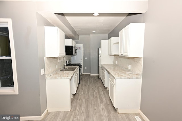 kitchen featuring decorative backsplash, light hardwood / wood-style floors, white cabinetry, and appliances with stainless steel finishes