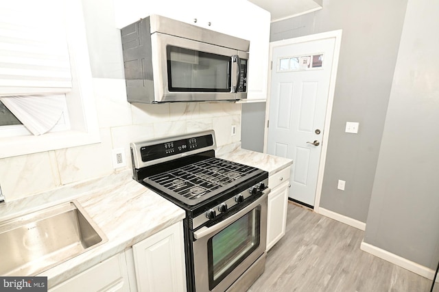 kitchen featuring sink, stainless steel appliances, tasteful backsplash, light hardwood / wood-style flooring, and white cabinets