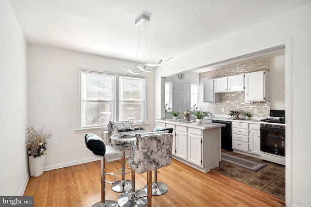 kitchen with range with gas stovetop, tasteful backsplash, dishwasher, white cabinets, and light hardwood / wood-style floors