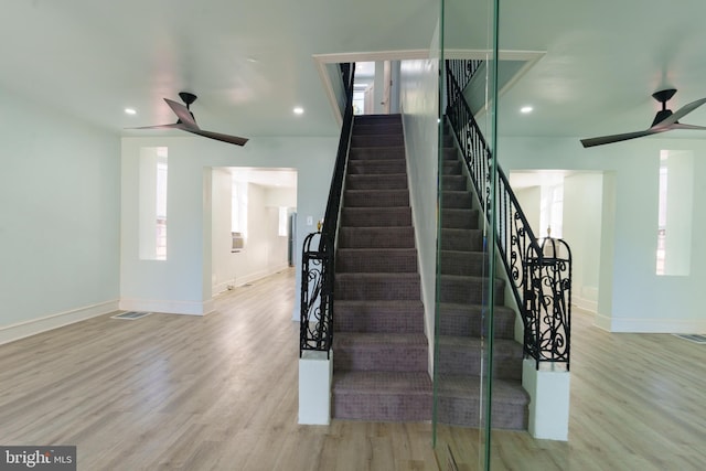 staircase featuring hardwood / wood-style floors, ceiling fan, and a healthy amount of sunlight