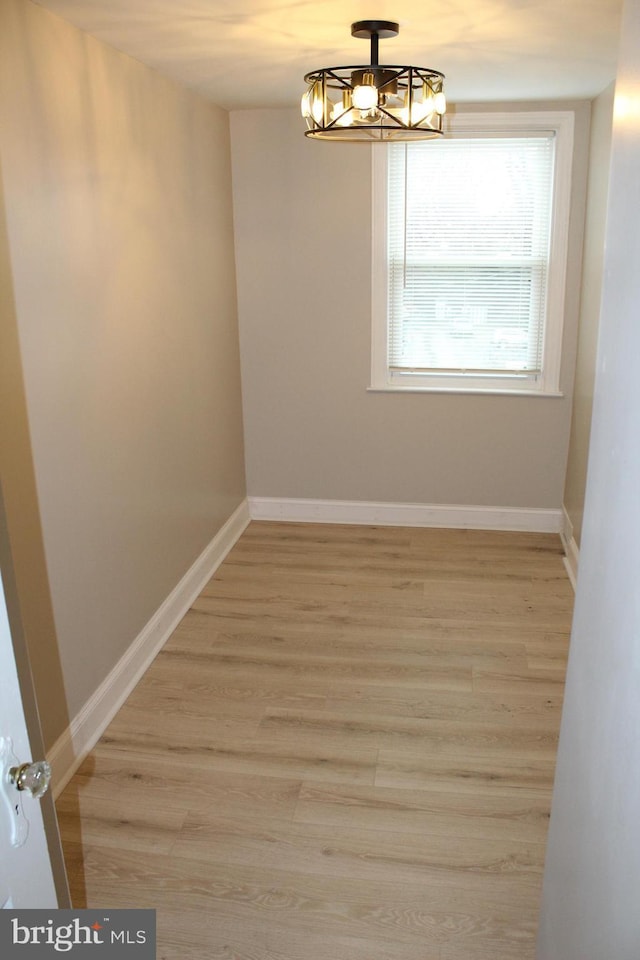 spare room featuring a notable chandelier and light hardwood / wood-style flooring