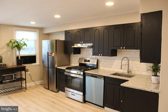 kitchen featuring light stone countertops, sink, appliances with stainless steel finishes, and light hardwood / wood-style flooring