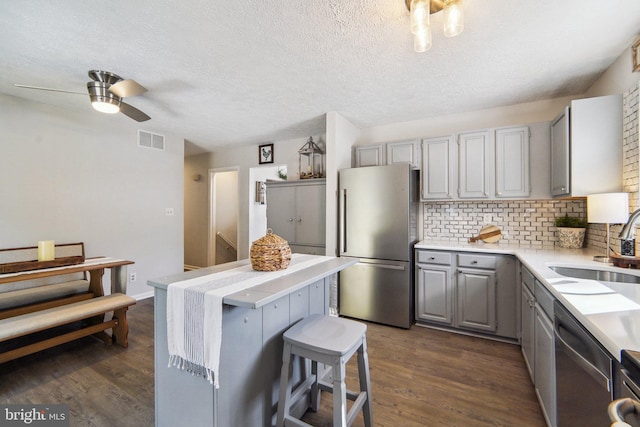 kitchen featuring gray cabinetry, stainless steel appliances, ceiling fan, sink, and tasteful backsplash