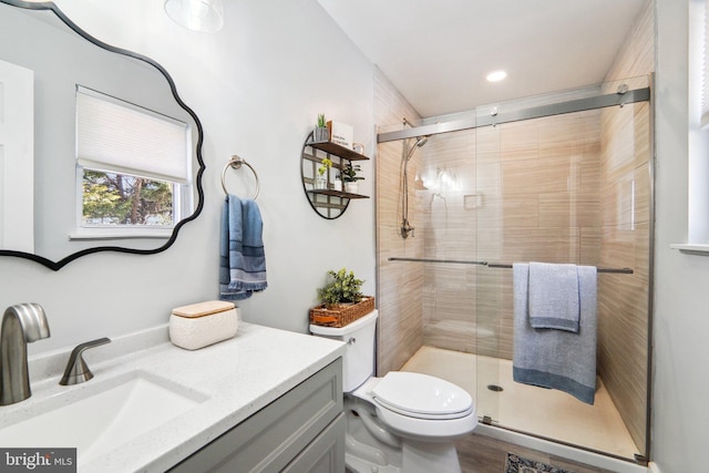 bathroom with toilet, an enclosed shower, and vanity