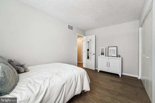 bedroom with a textured ceiling and dark hardwood / wood-style flooring