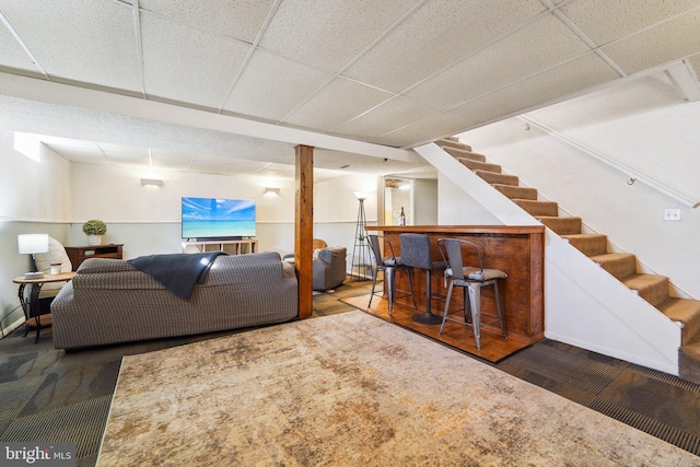 living room with a drop ceiling, hardwood / wood-style floors, and bar