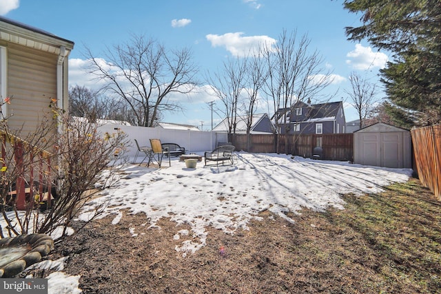 snowy yard featuring a patio, an outdoor fire pit, and a shed