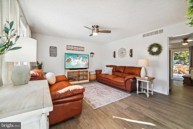 living room with a textured ceiling, ceiling fan, and dark hardwood / wood-style flooring