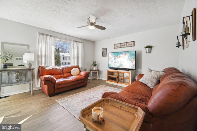 living room featuring a textured ceiling, ceiling fan, and light hardwood / wood-style floors