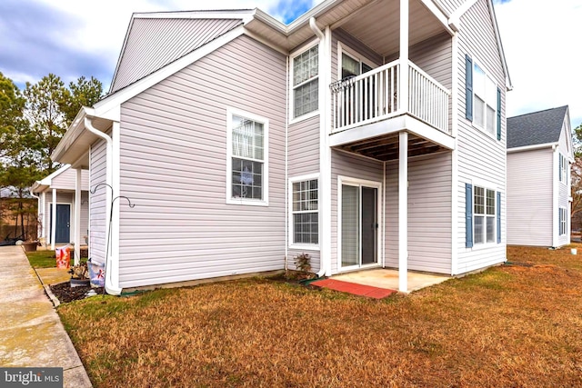 rear view of property featuring a balcony and a lawn