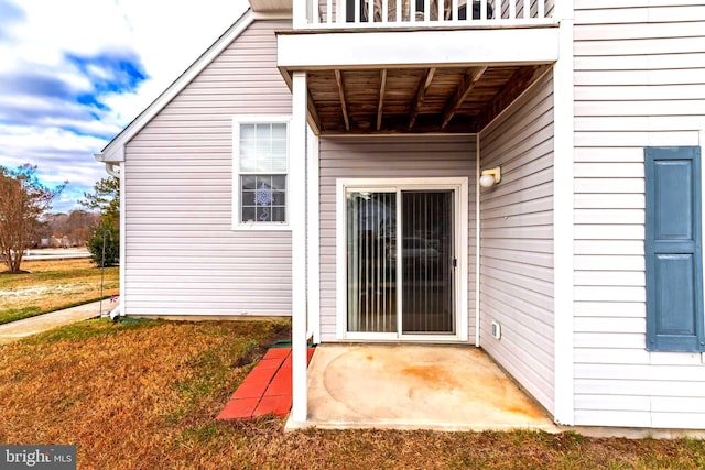 property entrance with a balcony and a lawn