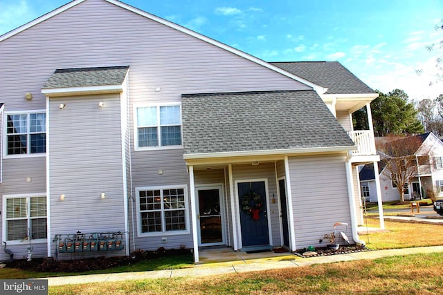 rear view of property featuring a yard and a balcony