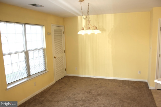 carpeted spare room featuring a healthy amount of sunlight and a chandelier