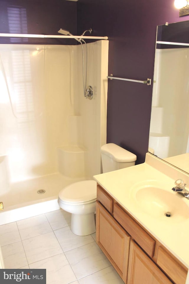 bathroom featuring a shower, vanity, tile patterned flooring, and toilet