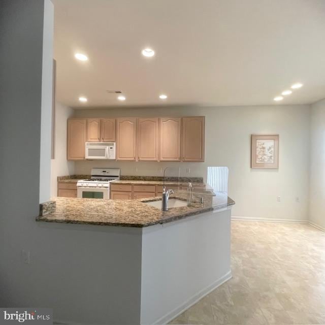 kitchen with kitchen peninsula, light brown cabinetry, white appliances, and sink