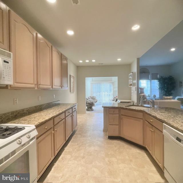 kitchen featuring white appliances, sink, and light brown cabinetry