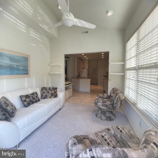 living room with light carpet, high vaulted ceiling, and ceiling fan