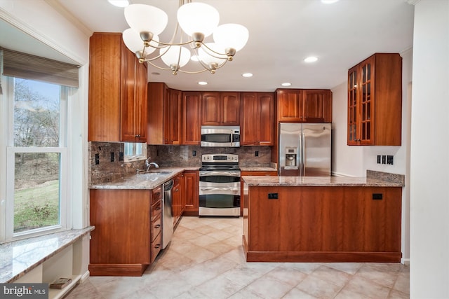 kitchen with appliances with stainless steel finishes, light stone counters, hanging light fixtures, and a notable chandelier