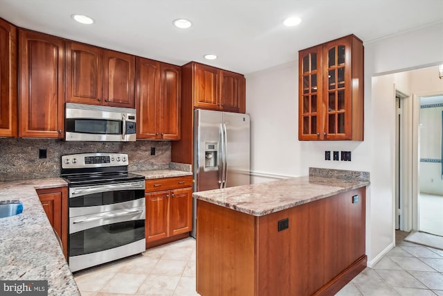 kitchen with decorative backsplash, appliances with stainless steel finishes, light tile patterned floors, and light stone counters