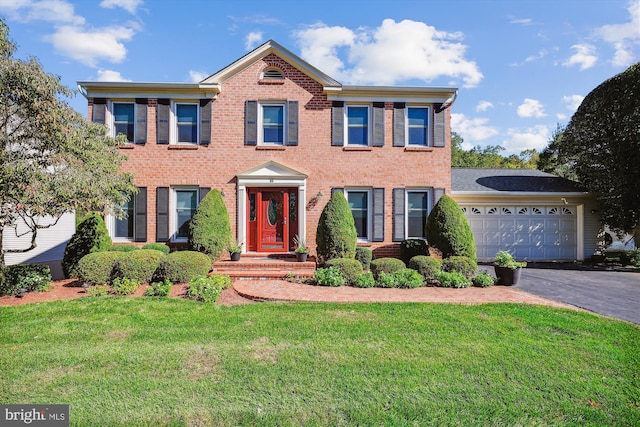 colonial home featuring a front yard and a garage