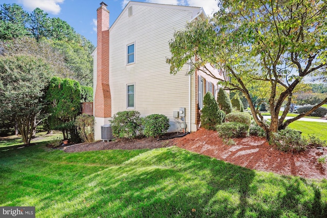 view of side of property with a lawn and central AC unit